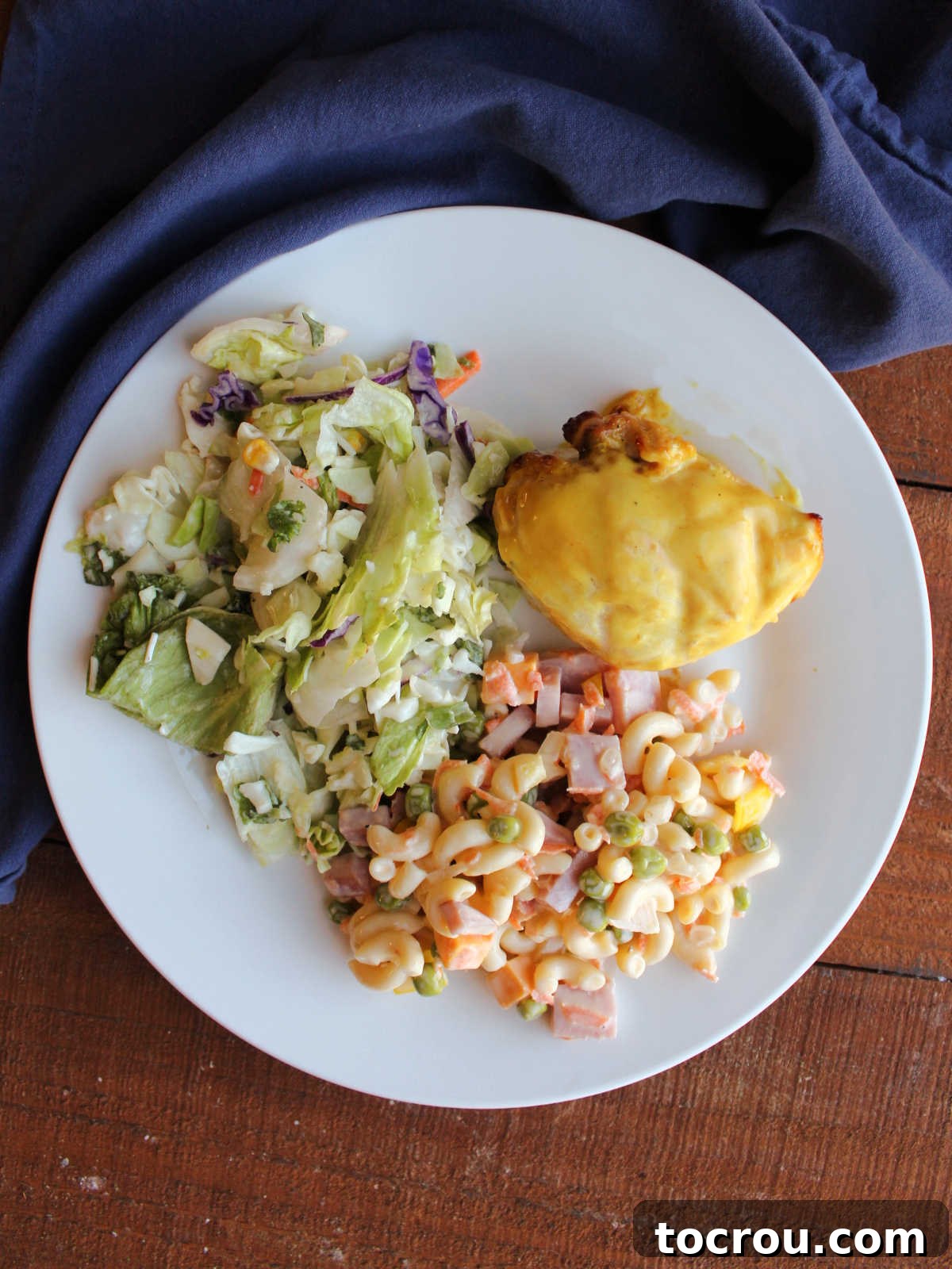 Dinner plate with sweet macaroni salad, grilled yellow chicken, and a green salad.
