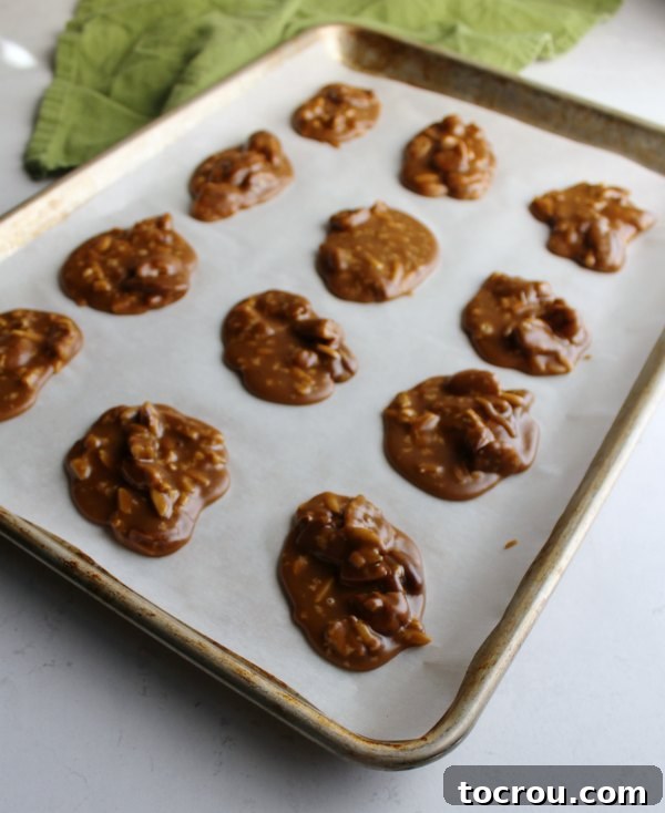Buttery Sweet Southern Pecan Pralines 3 A half sheet pan lined with parchment paper, showcasing neat scoops of freshly made pecan pralines cooling.