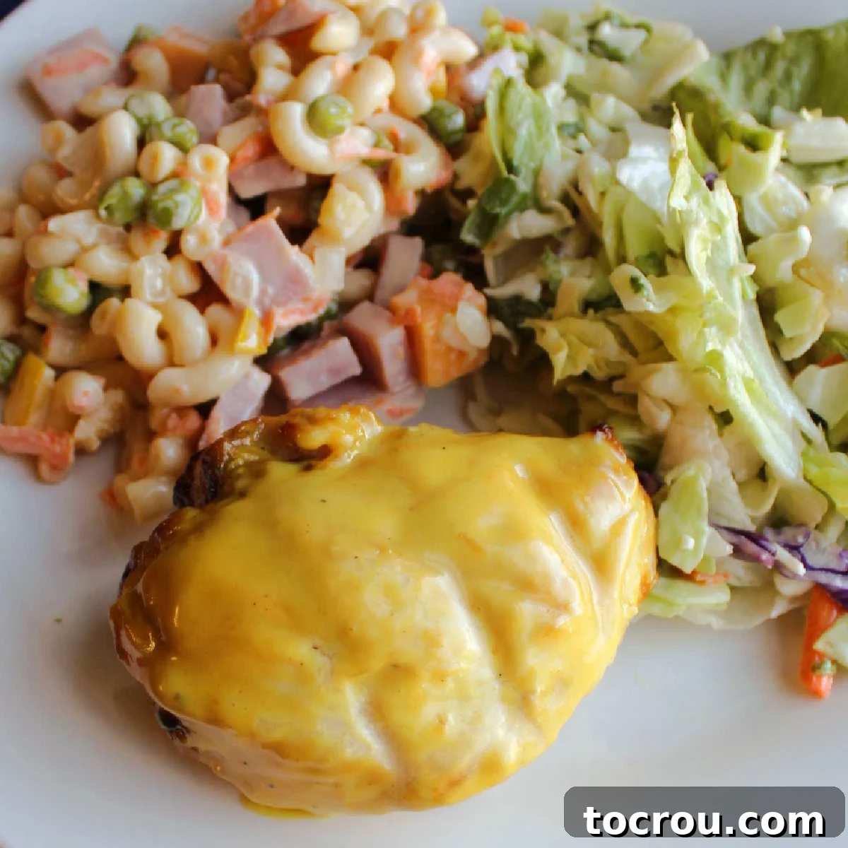 Tracy's Golden Hen 2 Close up of a grilled yellow chicken breast with mustard ranch sauce served with sweet macaroni salad and a green salad.