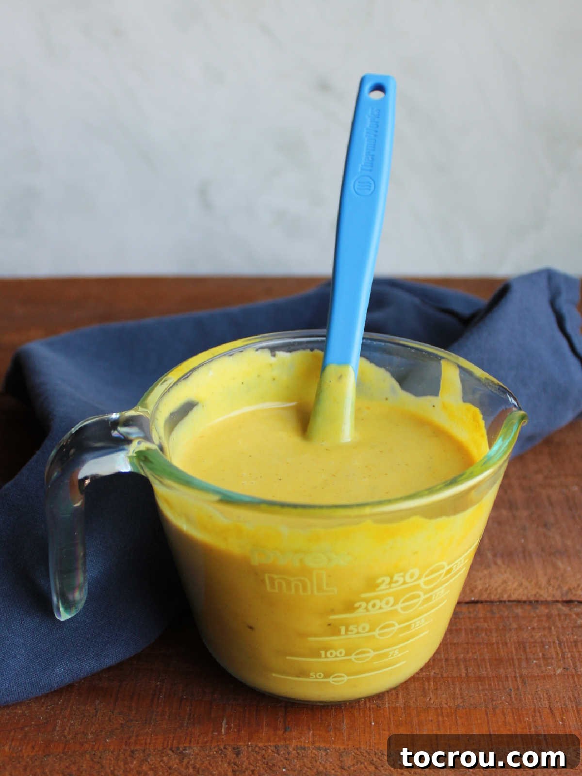 Tracy's Golden Hen 5 Measuring cup filled with mustard ranch sauce, ready to be put on chicken.