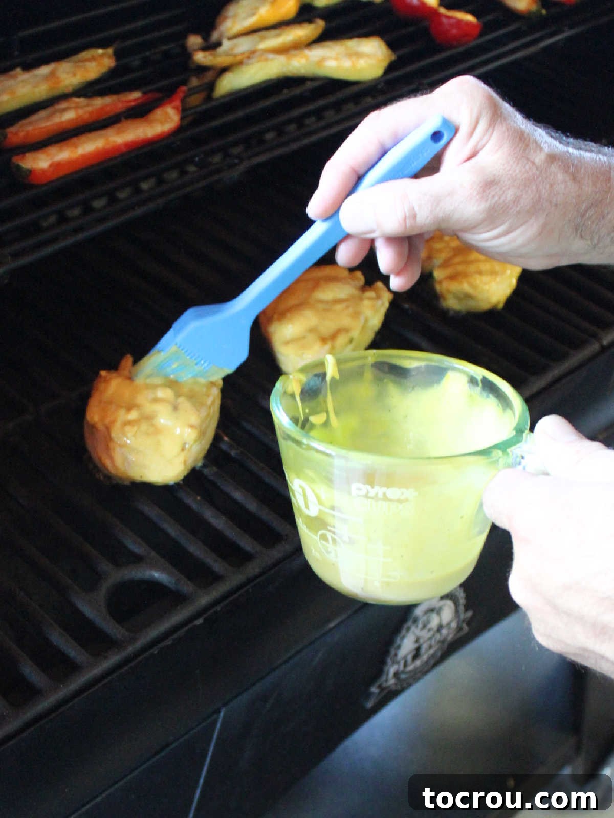 Tracy's Golden Hen 7 Brushing yellow mustard ranch sauce over chicken breasts on the pellet grill.