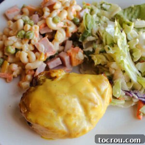 Close up of a grilled yellow chicken breast with mustard ranch sauce served with sweet macaroni salad and a green salad.