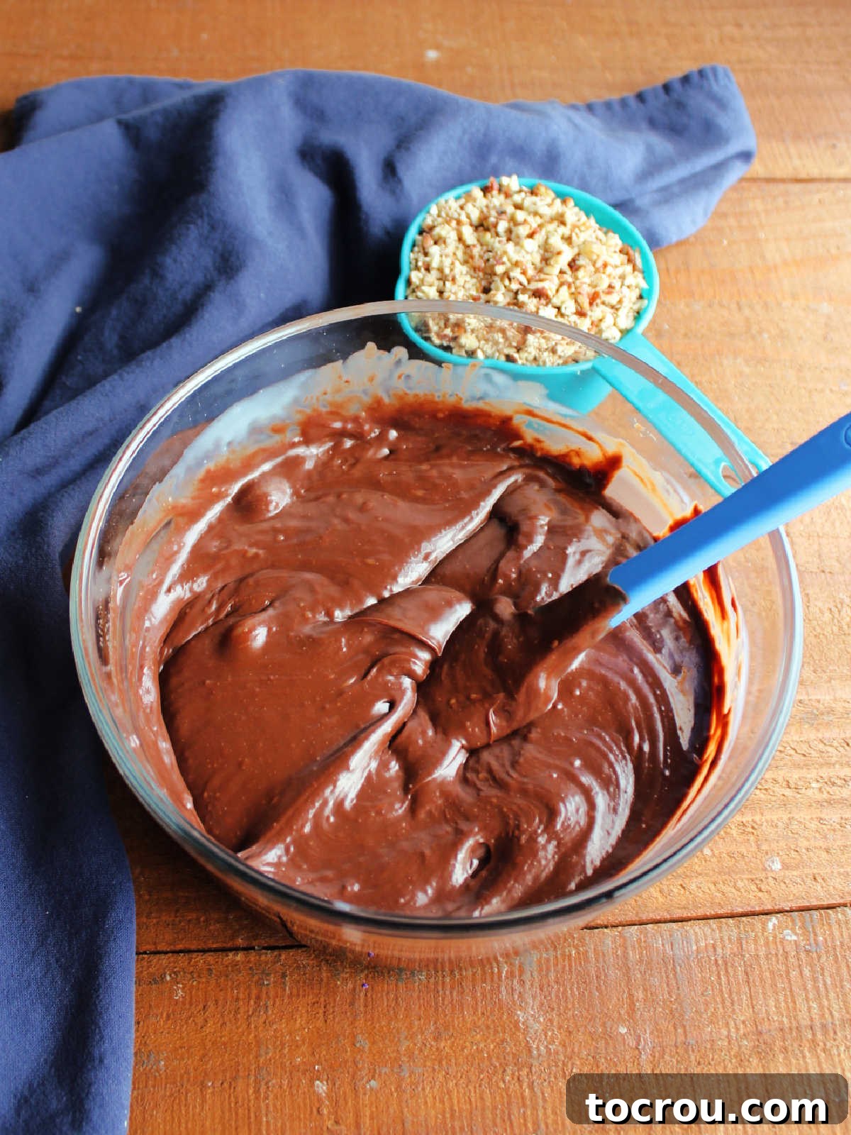 A glass mixing bowl holds a perfectly smooth, rich chocolate and condensed milk mixture, ready for the next step in creating delicious fudge ice cream cups.