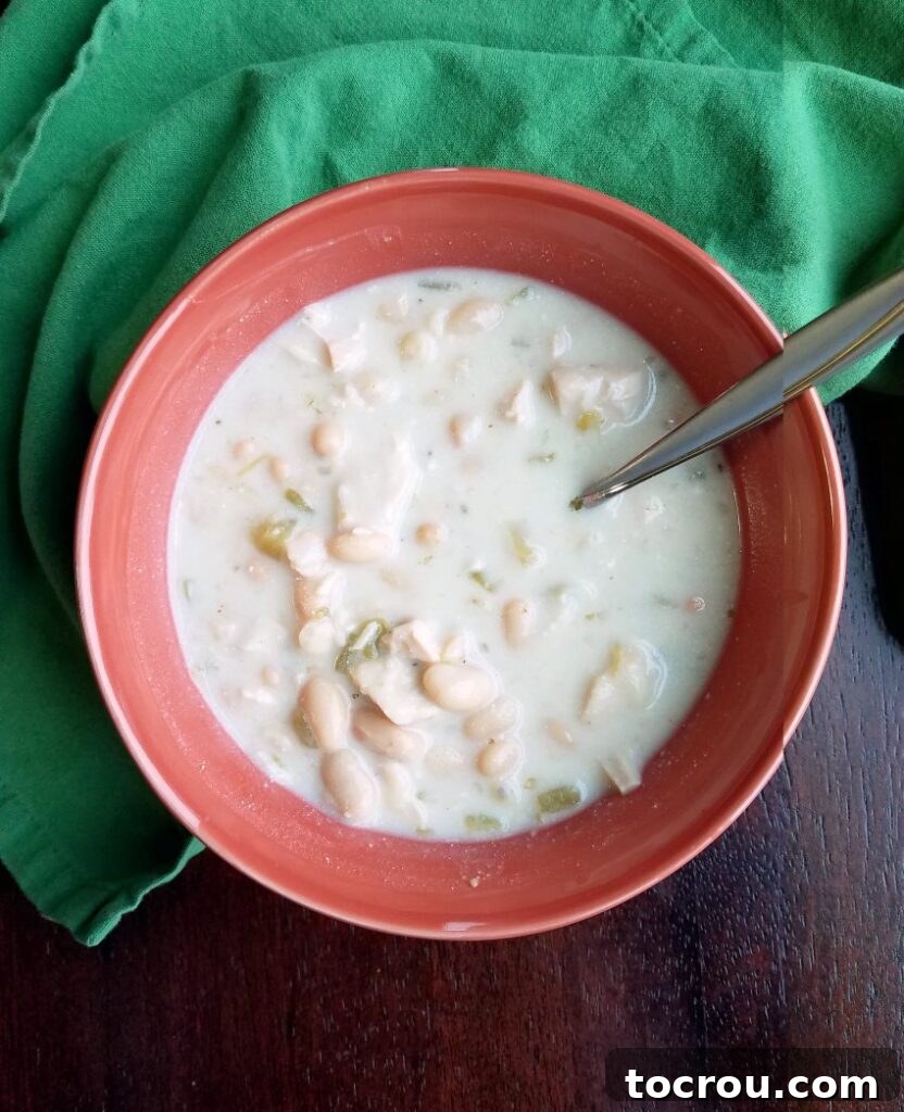 Best Creamy White Chicken Chili A bowl of rich, creamy white chicken chili with a spoon, ready to be savored.
