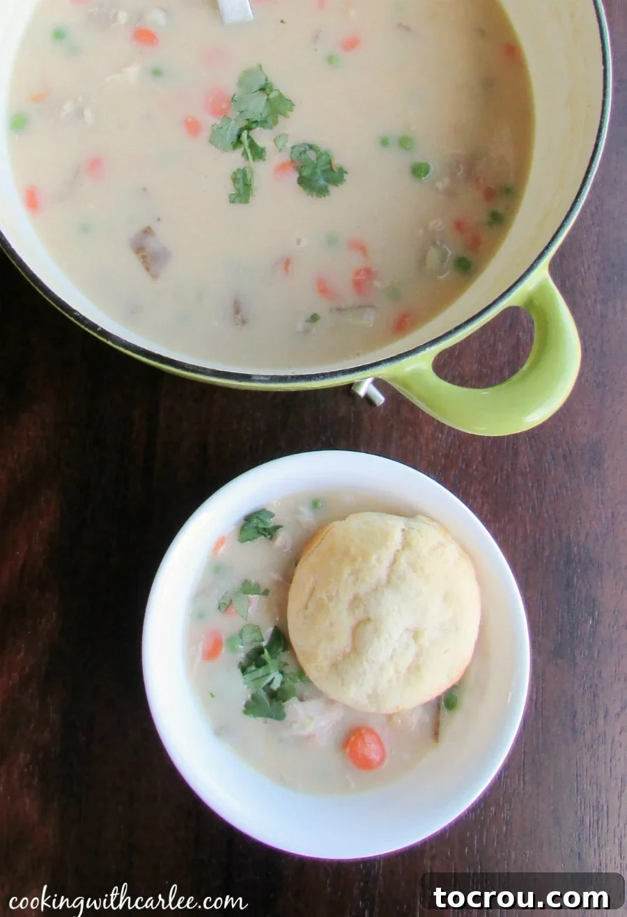 Comforting Creamy Chicken Pot Pie Soup Bowl of creamy chicken and veggie pot pie soup with a flaky biscuit topper.