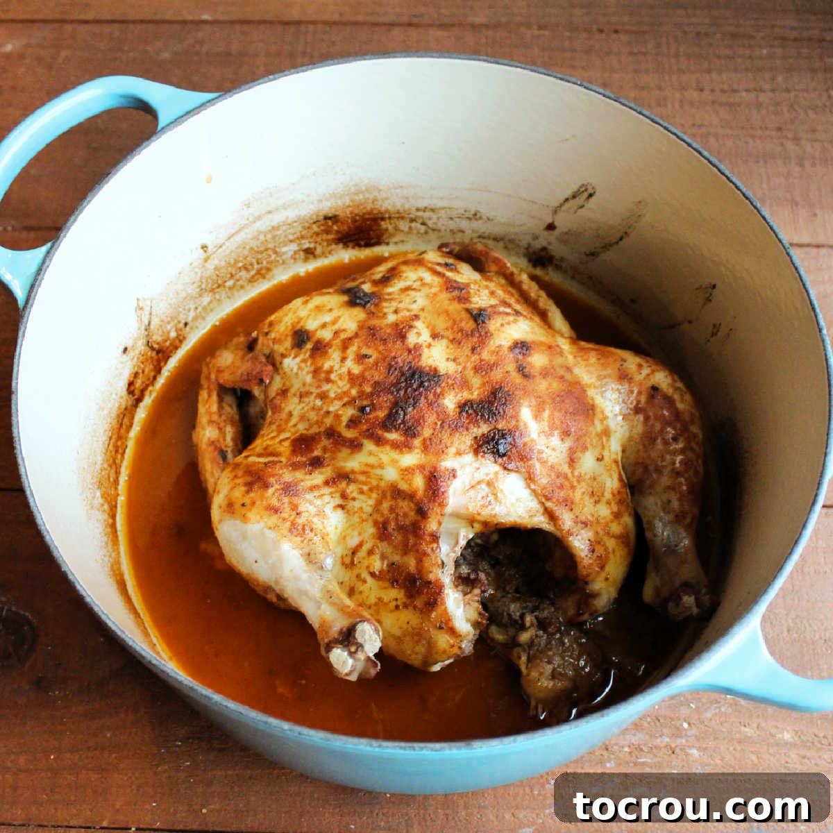 How to Roast a Juicy Chicken in a Dutch Oven Perfectly seasoned roast chicken in a large enameled Dutch oven with succulent cooking juices.