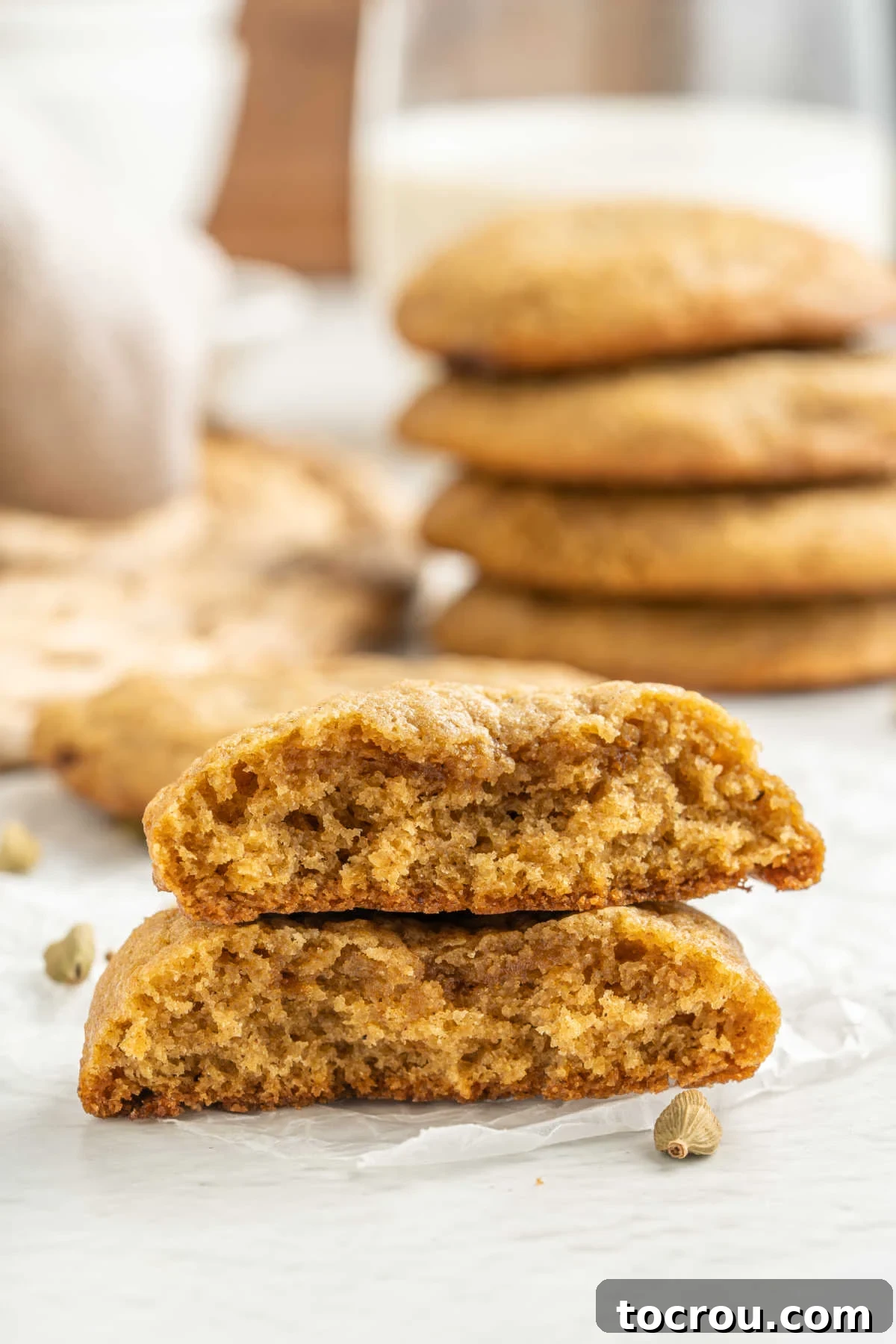 Chai Cookie with Chewy Texture Chai cookie, broken in half showing the chewy texture inside with more chai flavored cookies in the background.
