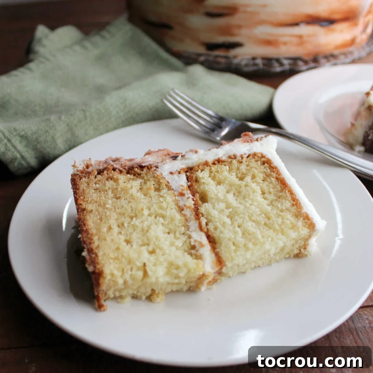 The 10-Inch Vanilla Classic 2 Slice of two layer 10 inch vanilla cake with white frosting, ready to eat.