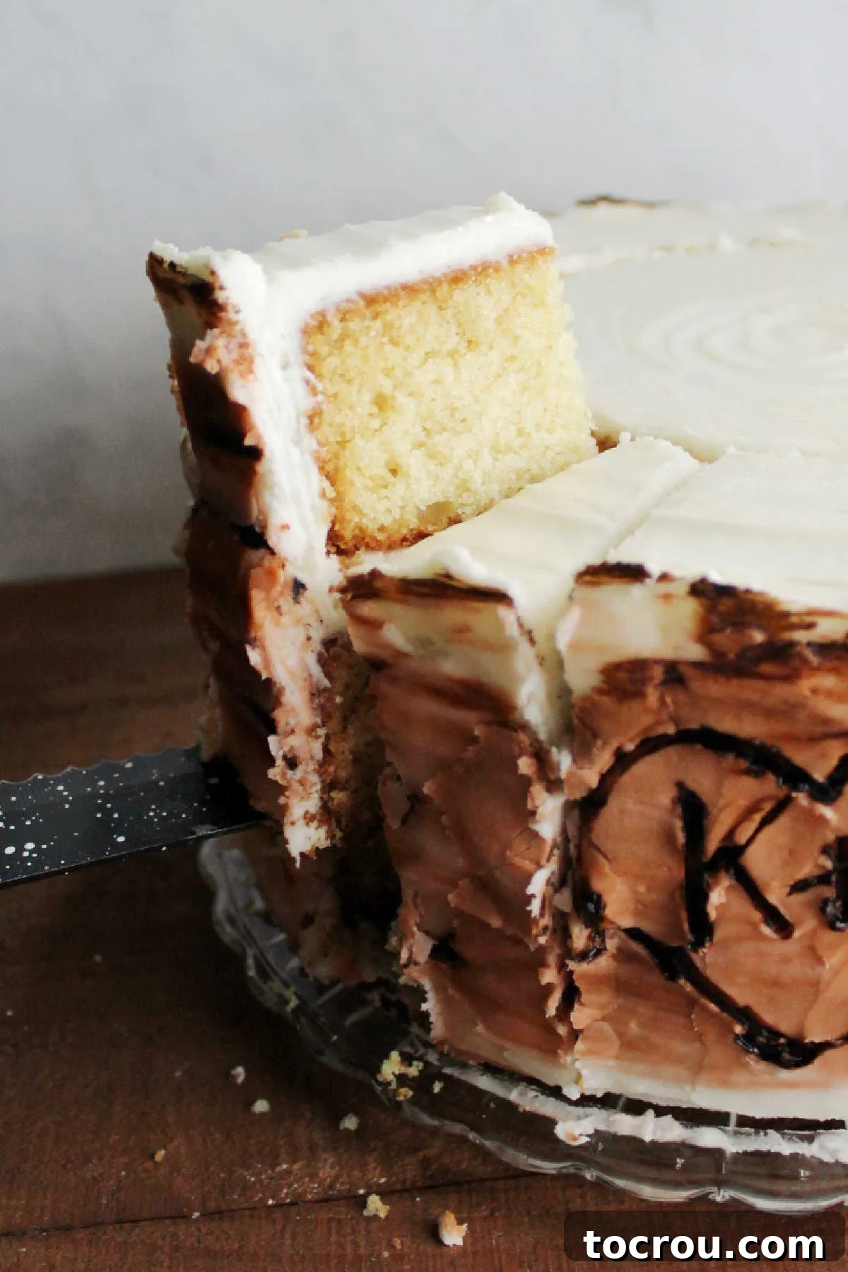 The 10-Inch Vanilla Classic 14 Lifting slice of vanilla layer cake out of larger cake.