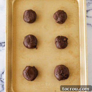 Scoops of chilled hot chocolate cookie dough on baking sheet, ready to go in the oven.