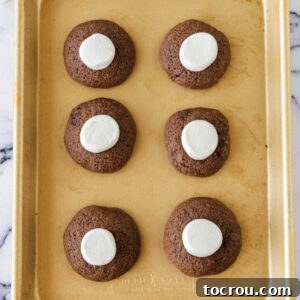 Putting marshmallow halves on partially baked chocolate cookie dough.