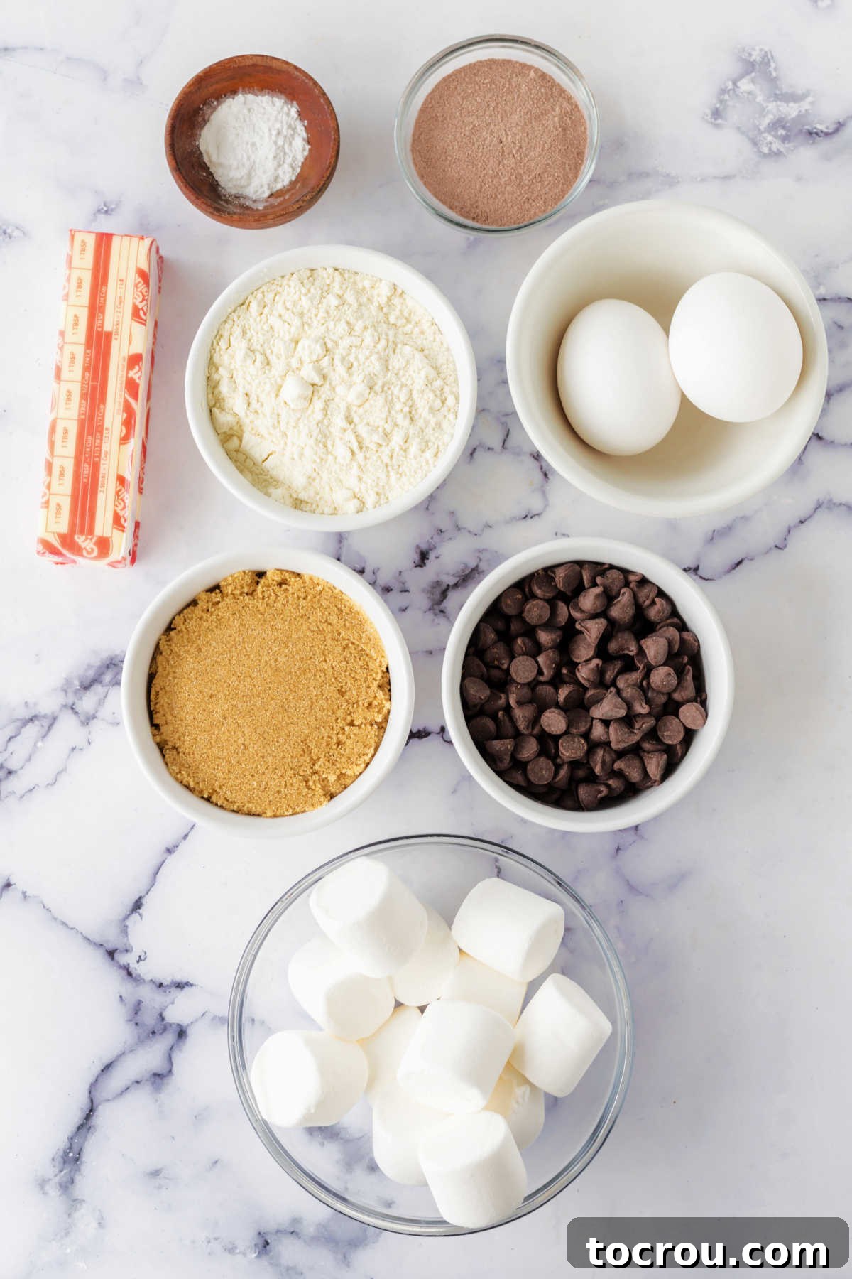 Cozy Hot Cocoa Cookies 4 Ingredients including butter, chocolate chips, brown sugar, flour, eggs, hot cocoa mix, baking powder, and marshmallows ready to be made into hot chocolate cookies.