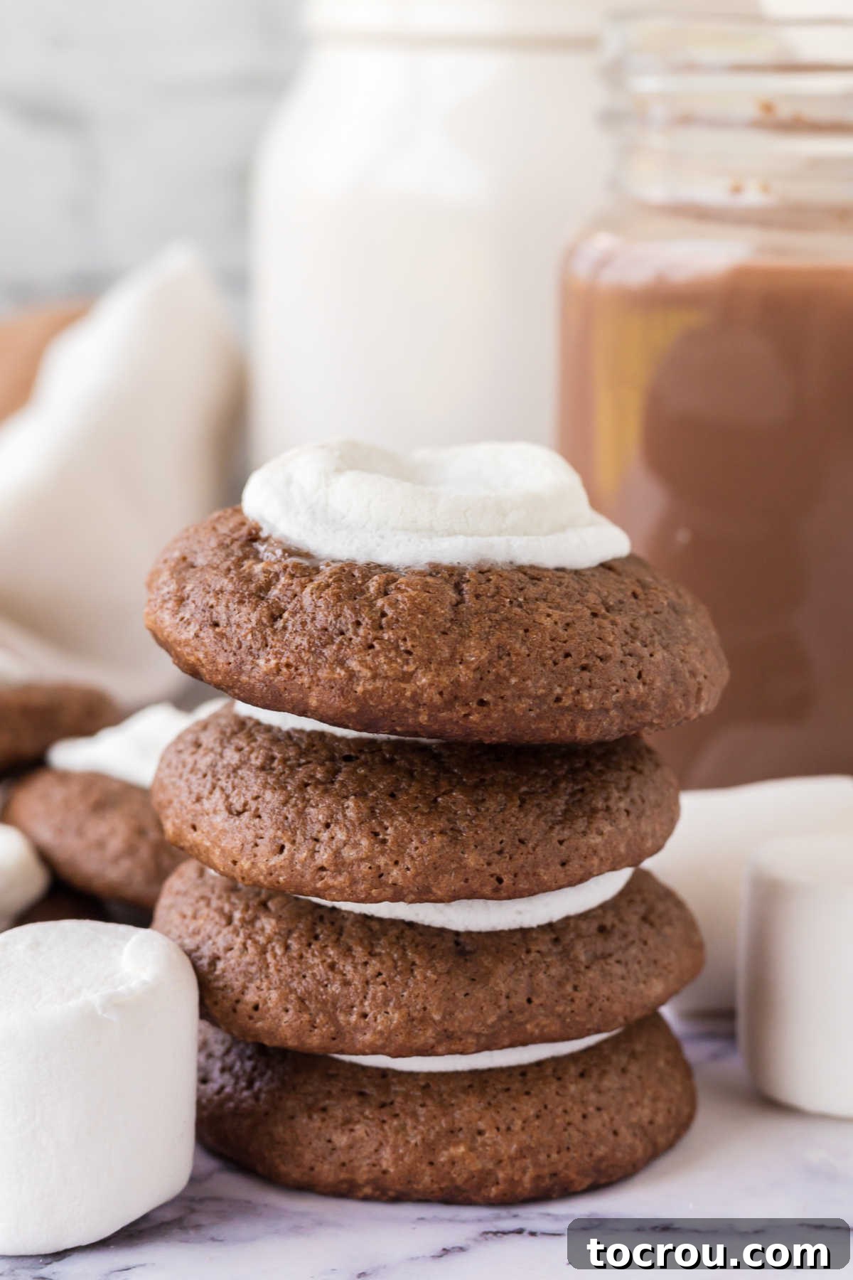 Cozy Hot Cocoa Cookies 6 Hot chocolate cookies stacked on top of each other showing thick chocolate cookie layer and melted marshmallow center.