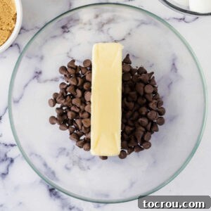 Mixing bowl with butter and chocolate chips inside, ready to be melted together.