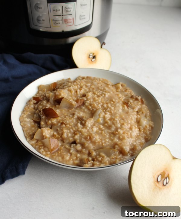 Honey Pear Oatmeal Ready to Serve Bowl of cooked honey pear steel cut oatmeal with two fresh pear halves, with the Instant Pot in the background.