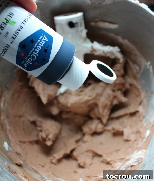 adding black food coloring gel to chocolate frosting to make black frosting