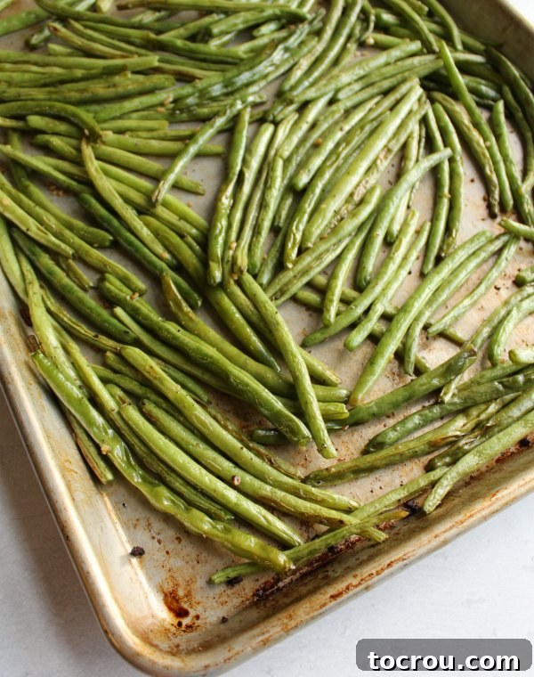 A baking sheet filled with golden-brown roasted green beans, fresh out of the hot oven.