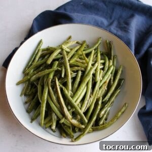 Close-up of a bowl of simple roasted green beans, highlighting their vibrant color and slightly charred texture.