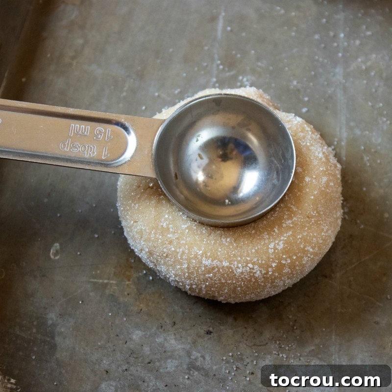 Jelly-Kissed Peanut Butter Bites 5 A teaspoon creating a perfect circular indent in a ball of peanut butter cookie dough.