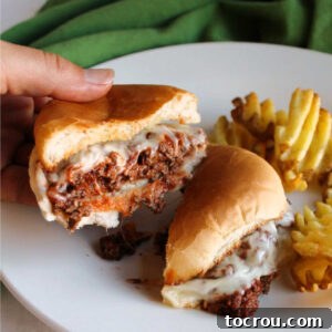 A delightful pizza burger, cut in half, showcasing its rich, melted cheese and savory meat filling.