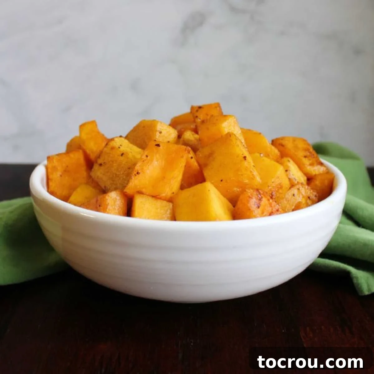 Make delicious roasted butternut squash quickly and easily in your air fryer. It is a great way to get a flavorful veggie side on your dinner plate! serving bowl filled with cubes of air fryer roasted butternut squash.