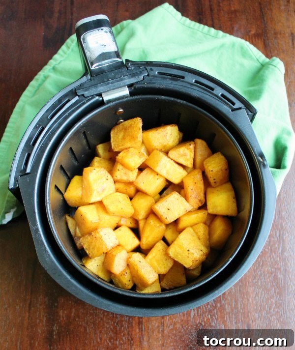 Crispy Air Fryer Butternut Squash 3 air fryer basket with roasted butternut squash cubes in it.