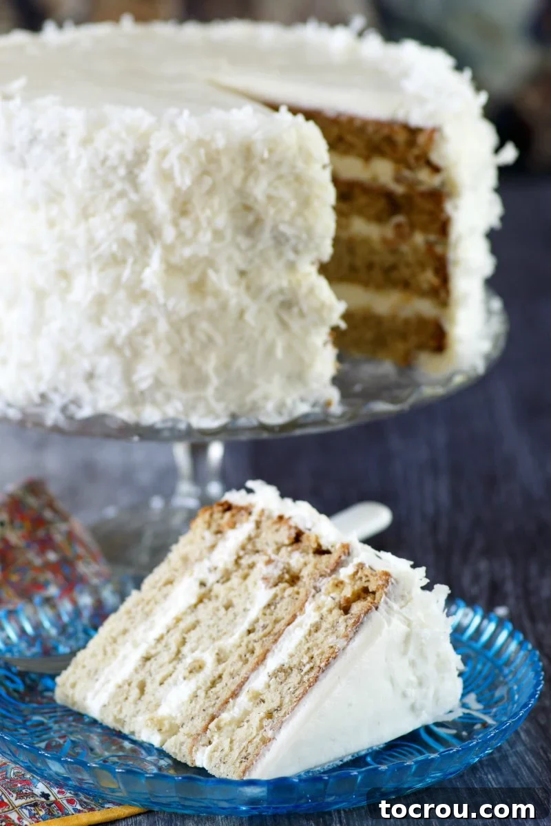 slice of layered banana cake with fluffy white meringue frosting and coconut.