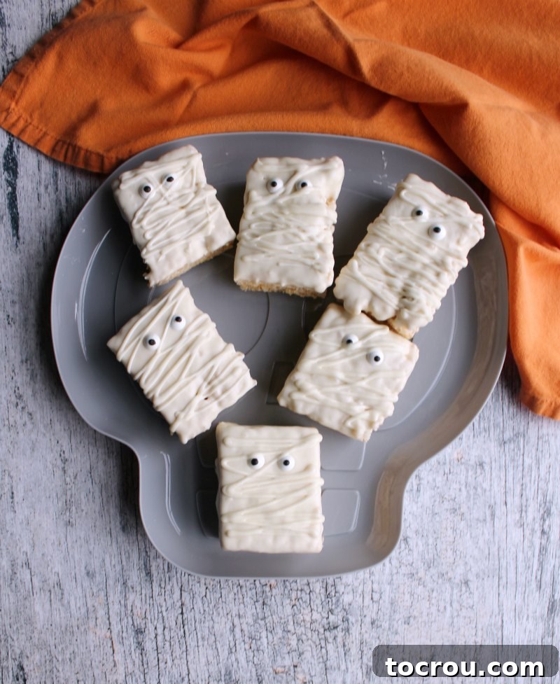 A skull-shaped serving platter artfully arranged with finished Rice Krispie treat mummies, ready for a Halloween party.