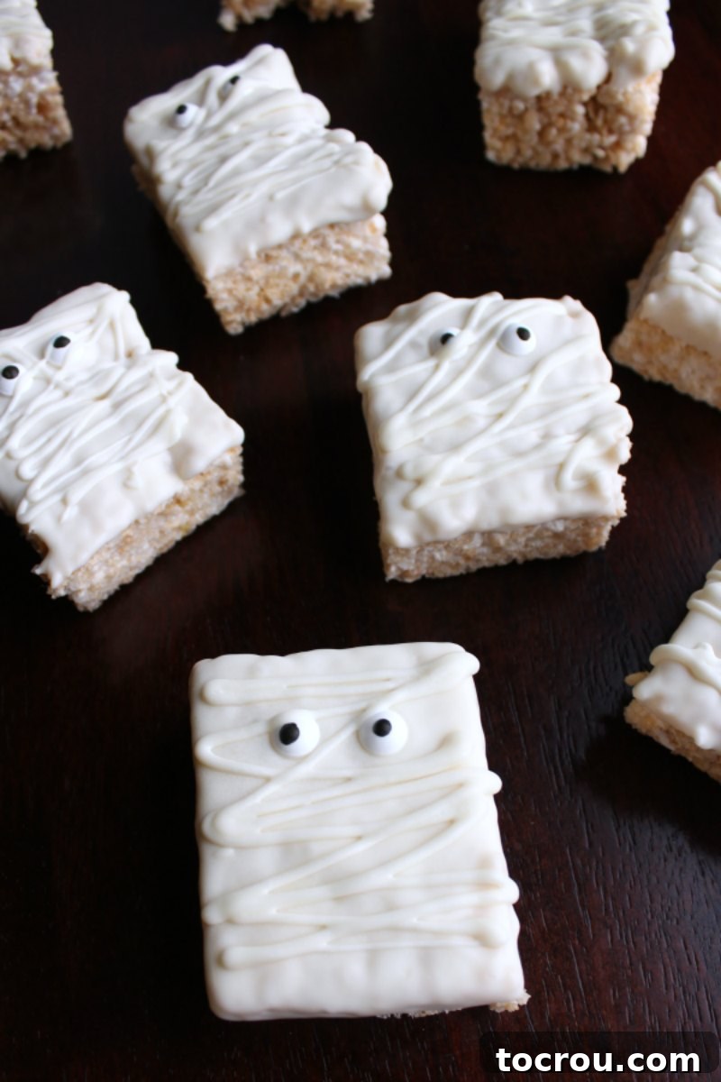 Close-up of a finished mummy Rice Krispie treat, showcasing the white chocolate bandages and candy eyes, ready for enjoyment.