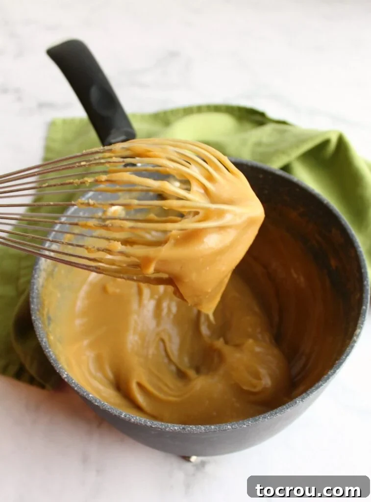 smooth brown sugar custard mixture on whisk over saucepan for german buttercream
