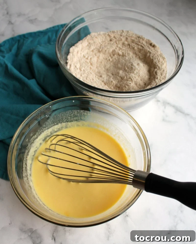 Two bowls, one containing a mix of wet ingredients and the other dry ingredients, perfectly prepped for making a delicious rustic apple cake.