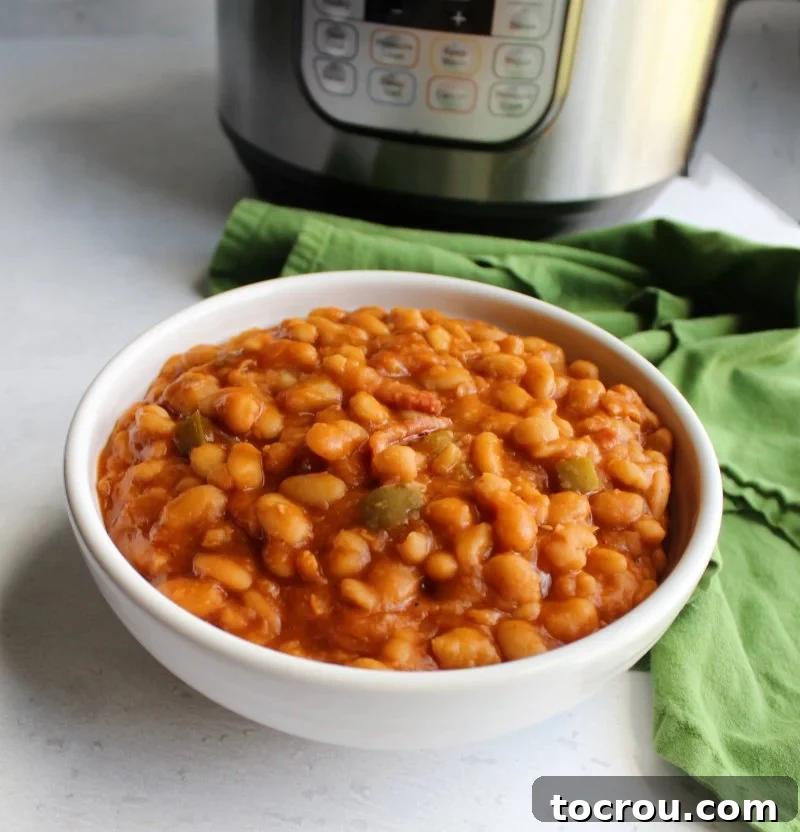 Looking across a bowl of homemade maple baked beans with a pressure cooker in the background.