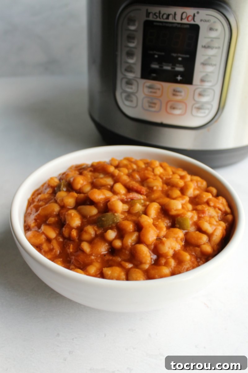 White serving bowl filled with maple bacon baked beans in front of an Instant Pot.