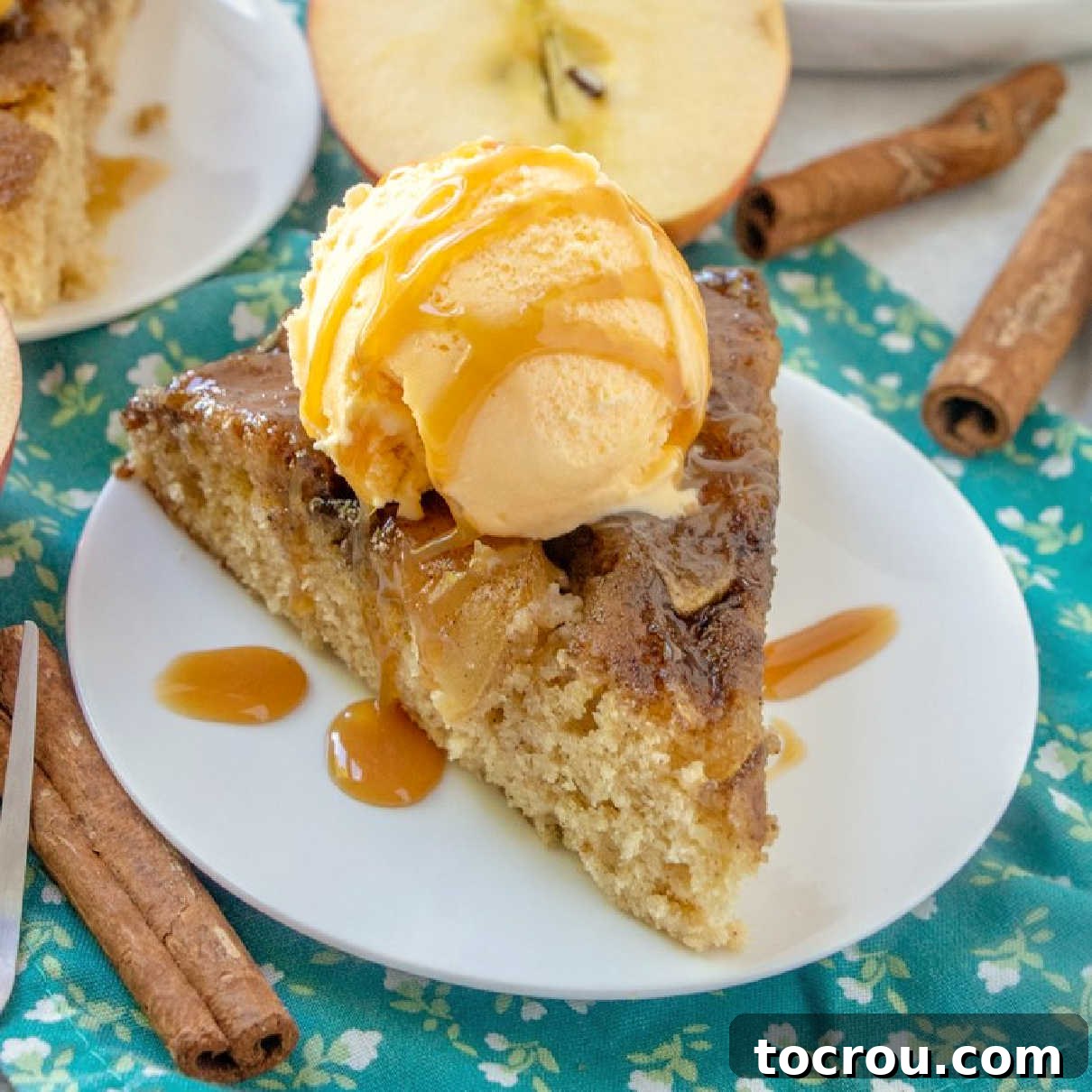 A slice of warm delicious down home caramel apple upside down skillet cake is sure to bring a smile to your face. Add a scoop of ice cream to this spiced cake for an extra special fall treat. close slice of warm upside down caramel apple skillet cake with scoop of ice cream and drizzle of caramel sauce.