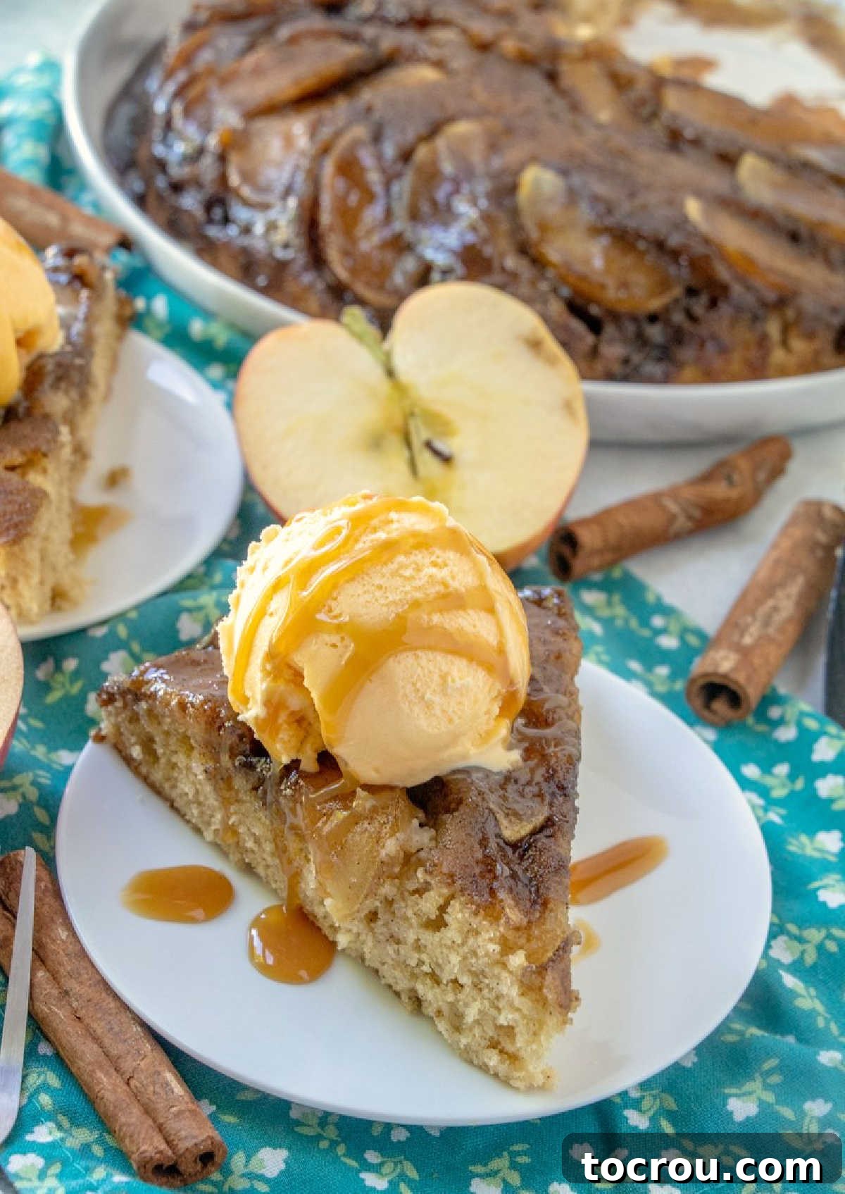 Gooey Caramel Apple Upside Down Cake 5 Slice of upside down apple skillet cake ready to eat with remaining caramel apple cake in the background.