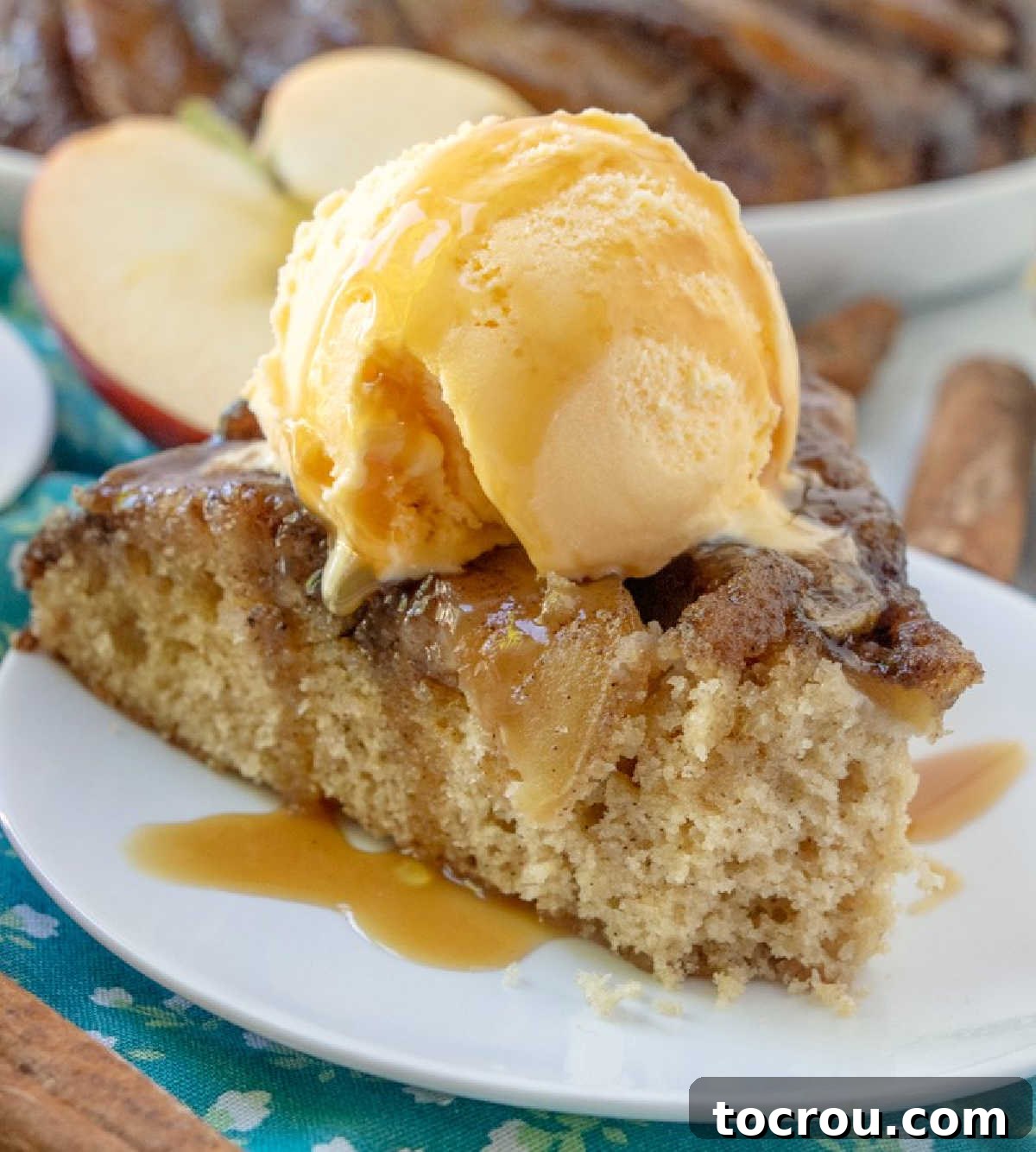 Gooey Caramel Apple Upside Down Cake 6 Close up of slice of caramel apple upside down cake showing soft spice cake topped with apples and caramel mixture topped with vanilla ice cream.