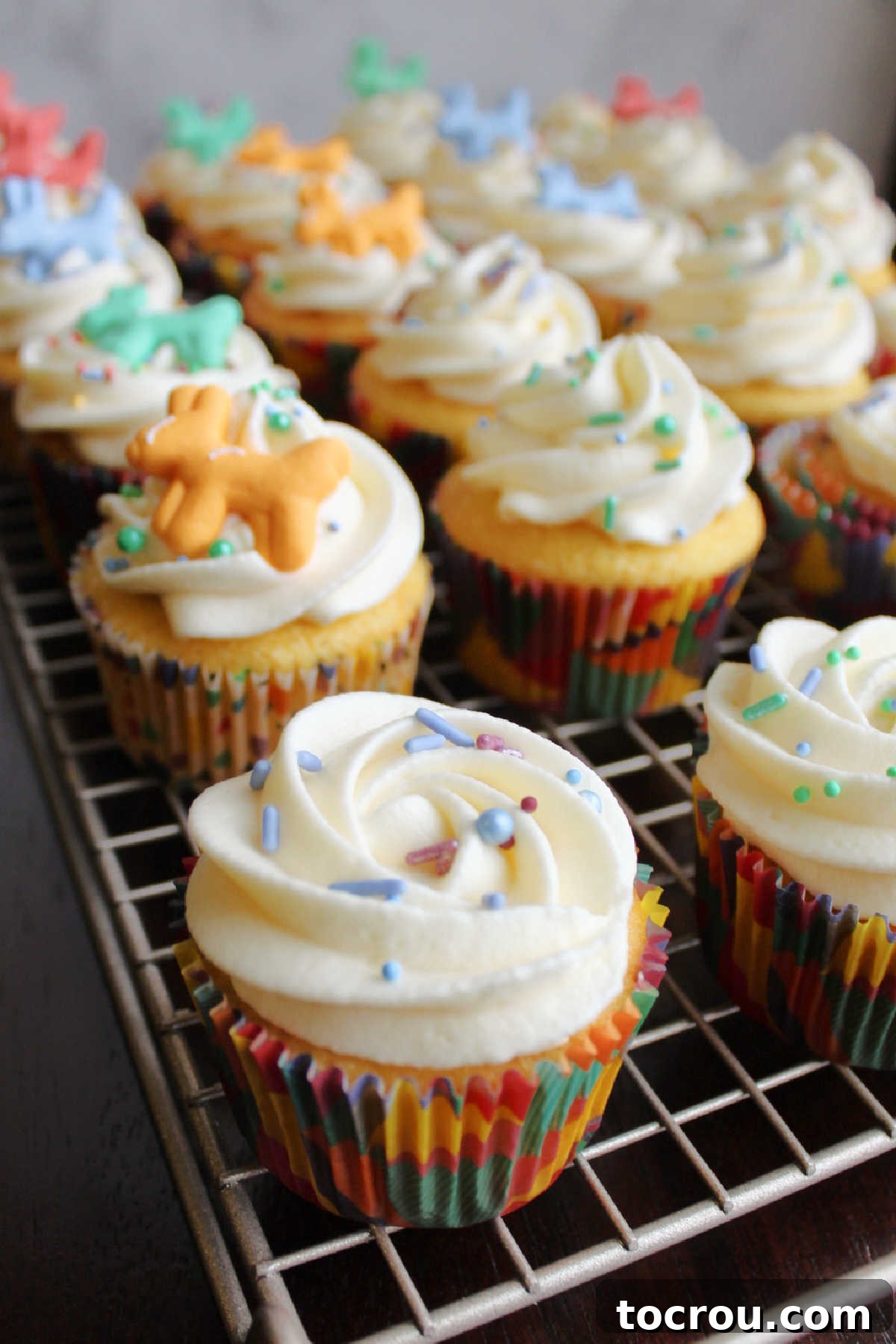 Swirls of russian buttercream piped onto cupcakes and topped with colorful sprinkles.