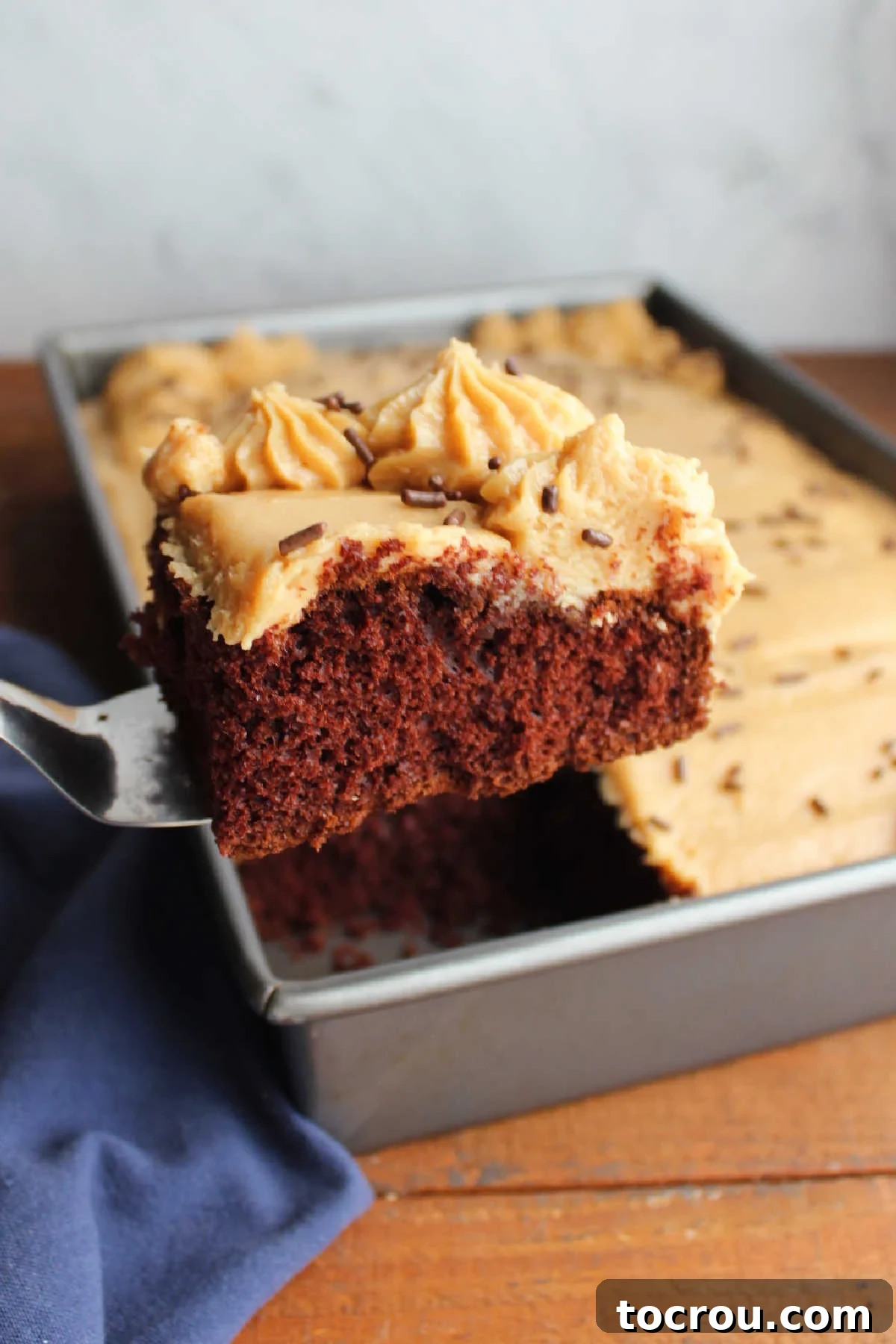 Spatula lifting a piece of cake topped with peanut butter frosting.