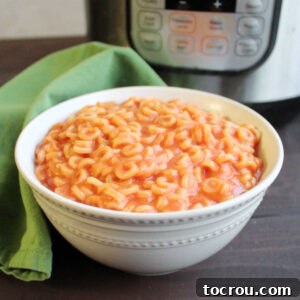 A close-up of a bowl filled with homemade Instant Pot Spaghettios, gleaming in front of the Instant Pot, symbolizing comfort and ease.