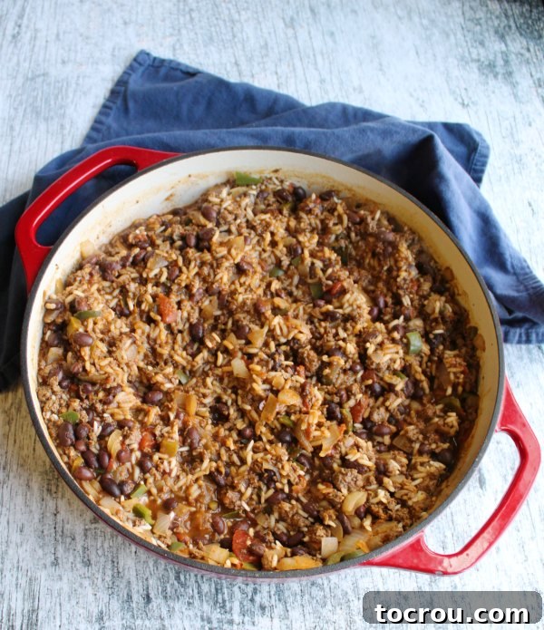 Taco Rice Skillet Fiesta 3 red enameled cast iron skillet full of one pan taco rice skillet meal before the cheese is melted on top