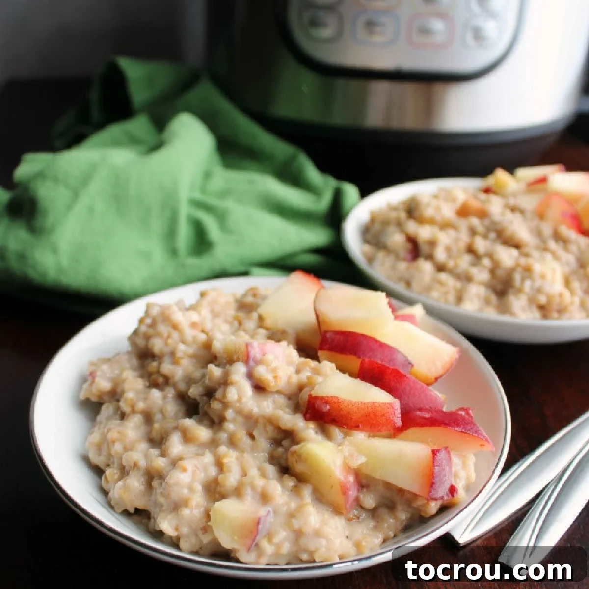 Two bowls of creamy maple cinnamon steel cut oatmeal with fresh peaches on top in front of an Instant Pot.
