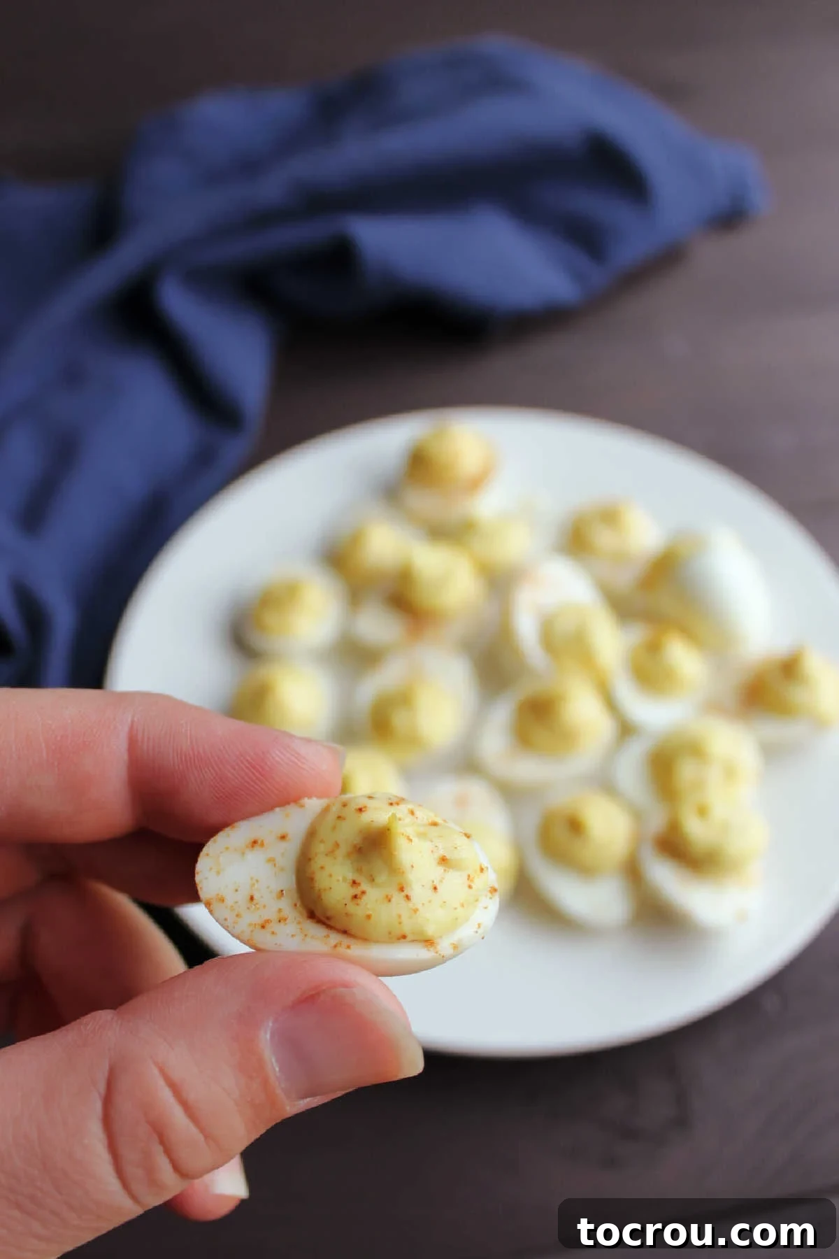 Tiny deviled quail egg held delicately in hand, ready to be enjoyed.