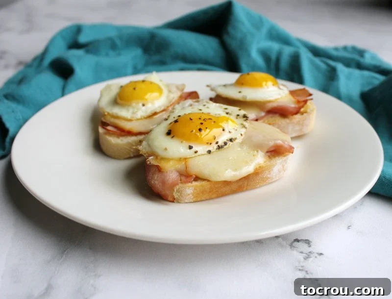 Plate of ham and cheese crostini, each topped with a perfectly fried quail egg.