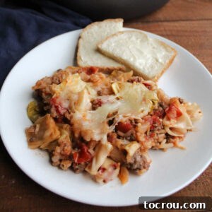 Plate of cabbage roll skillet meal topped with melted cheese and served with buttered bread.