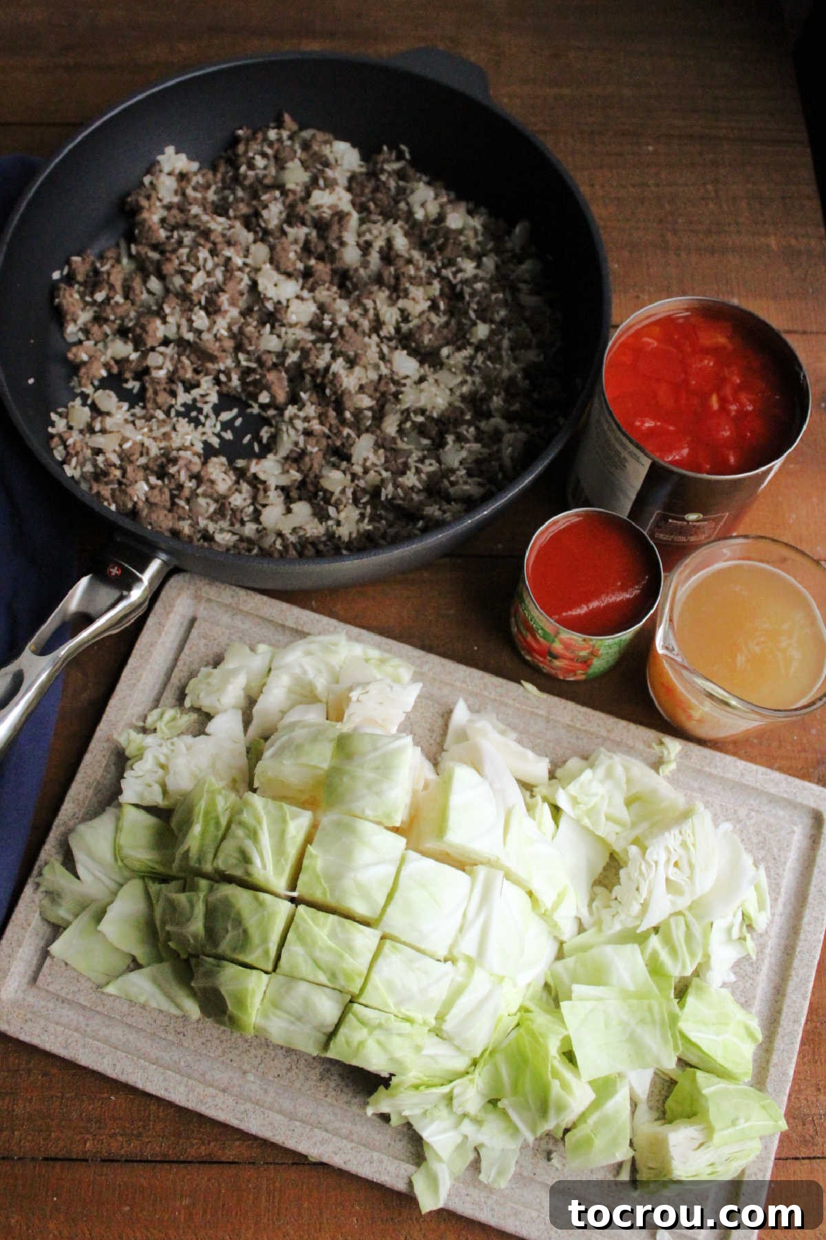 Key ingredients for an unstuffed cabbage roll skillet meal laid out, including ground beef, chopped cabbage, onions, tomato sauce, diced tomatoes, and beef broth.