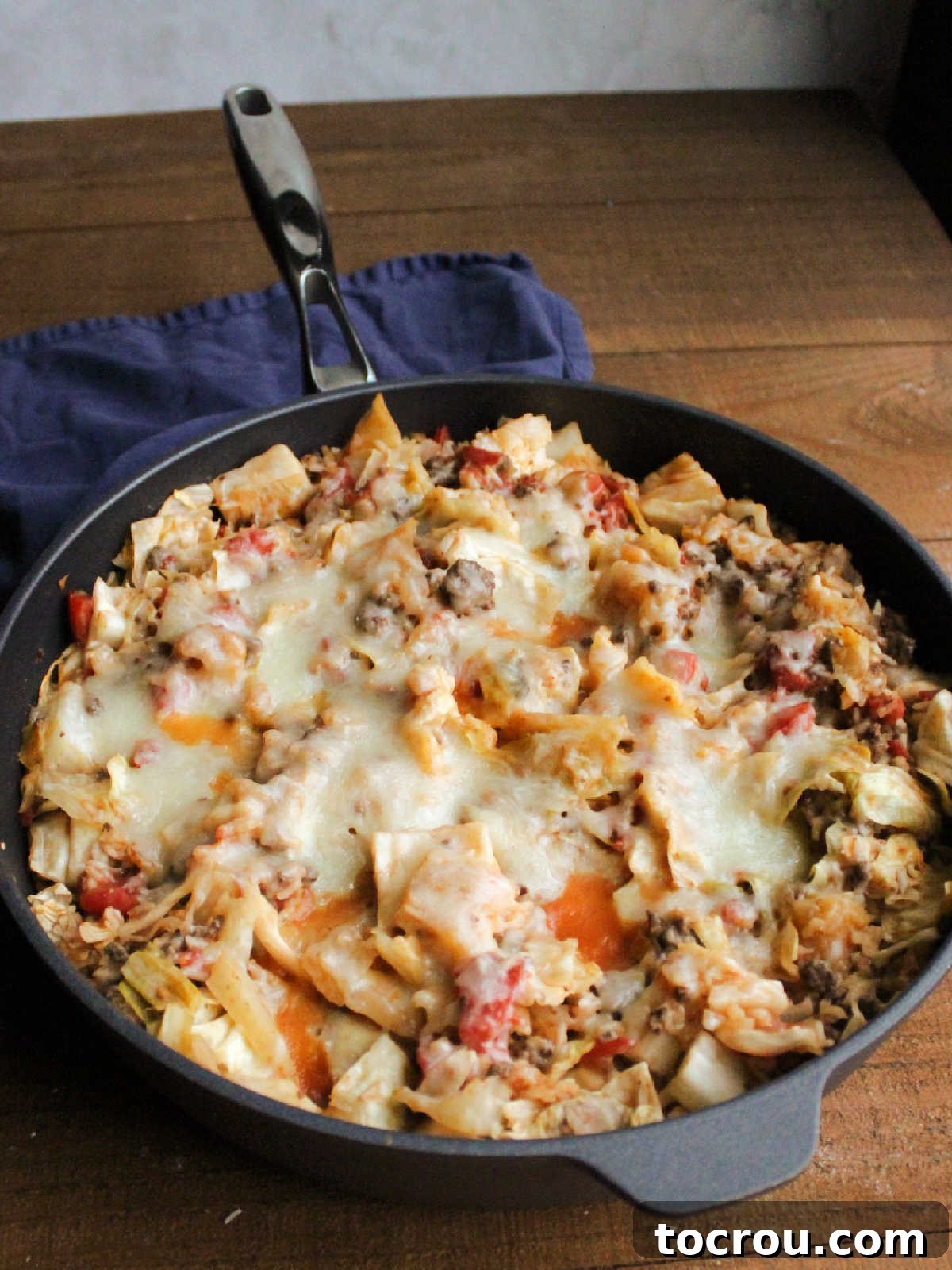 The unstuffed cabbage roll skillet meal after being topped with mozzarella cheese, which has melted into a golden, bubbly layer, ready to be served.