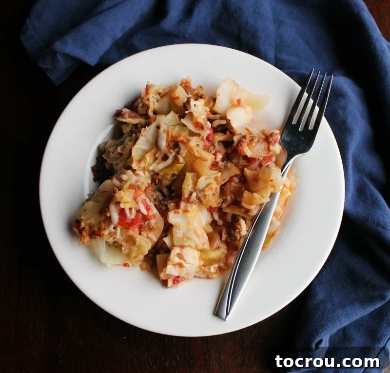 A dinner plate filled with a generous serving of unstuffed cabbage roll skillet dinner, accompanied by a fork, ready for enjoyment.
