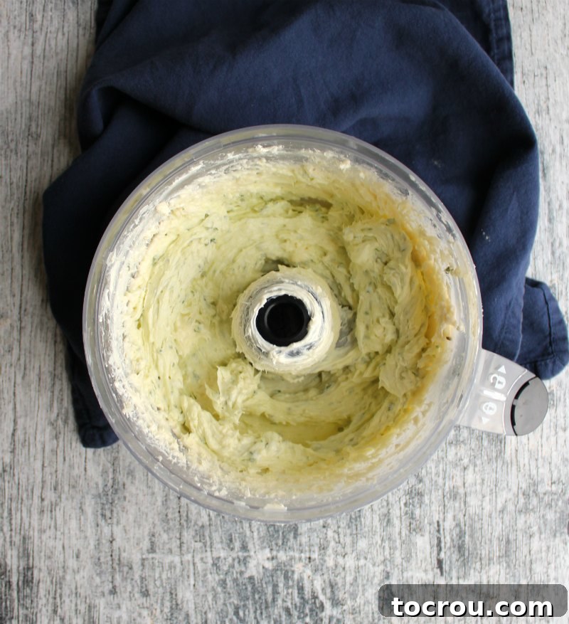Food processor full of creamy and herby Havarti cheese ball mixture ready to be rolled into a ball.