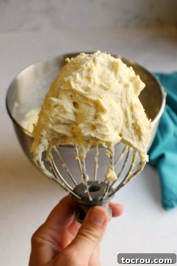 Decadent Black Forest Sheet Cake 5 Hand holding a mixer beater full of custardy German buttercream, smooth and ready to spread.