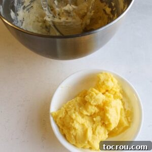 Whipped butter in mixer bowl next to bowl of thick dough like chilled custard, ready to be incorporated into buttercream.